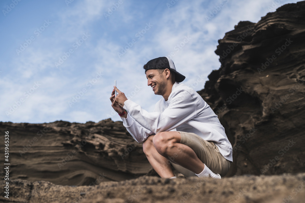 Smiling male tourist through smart phone at El golfo, Lanzarote, Spain Smiling male tourist through smart phone at El golfo, Lanzarote, Spain