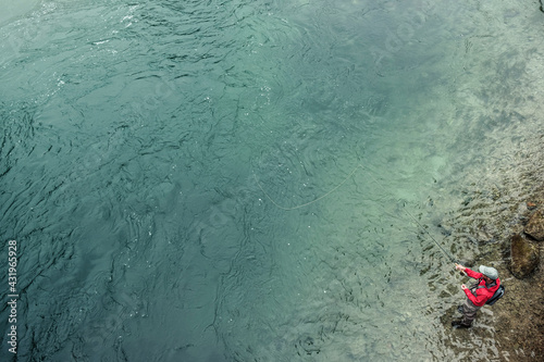 Mature man fishing through fishing line while standing in river at Loisach river at Kochelsee, Bavaria, Germany photo