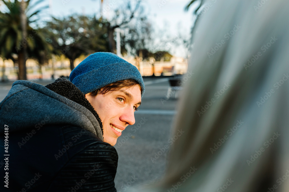 Smiling young man wearing knit hat with girlfriend at promenade Smiling young man wearing knit hat with girlfriend at promenade