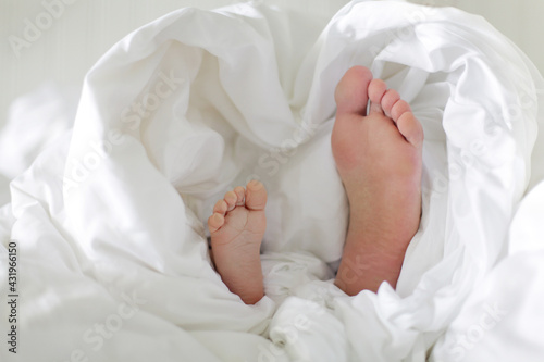 Father son feet together white heart shaped blanket. Fathers day, family love, parental care, father son together, family bonding, generation look alike concept