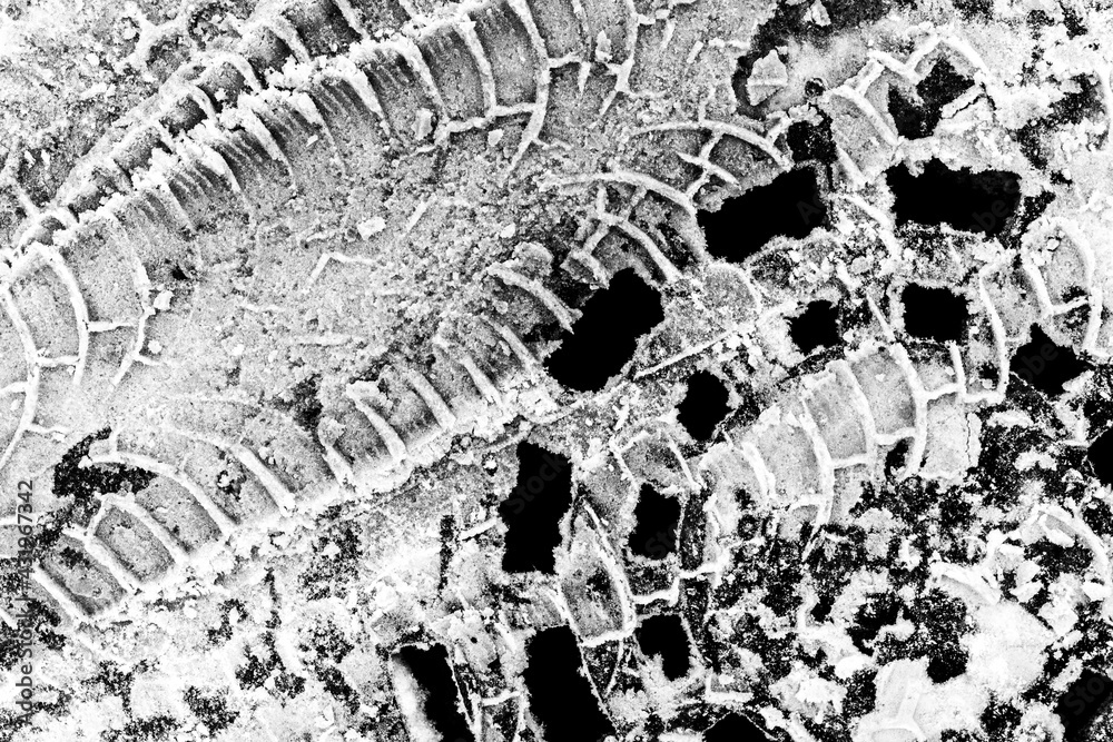 Fototapeta premium Cover manhole covered by snow and trace of car tires. Close up view from above