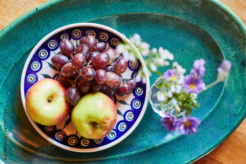 Bowl of fresh ripe grapes and apples with flower photo