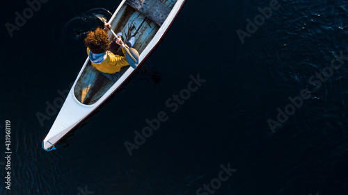 Young man paddling through oar while sitting in canoe on river