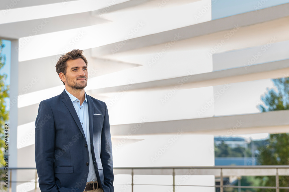 Mid adult businessman looking away while standing against office building Mid adult businessman looking away while standing against office building