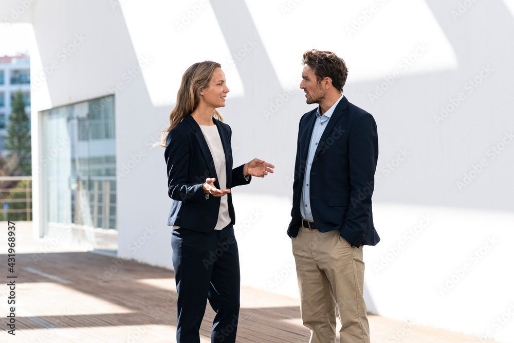 © steve brookland/Westend61 - Female entrepreneur having discussion with colleague while standing against wall