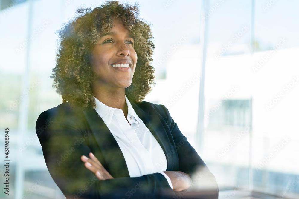 © steve brookland/Westend61 - Female professional smiling while looking through window at modern office