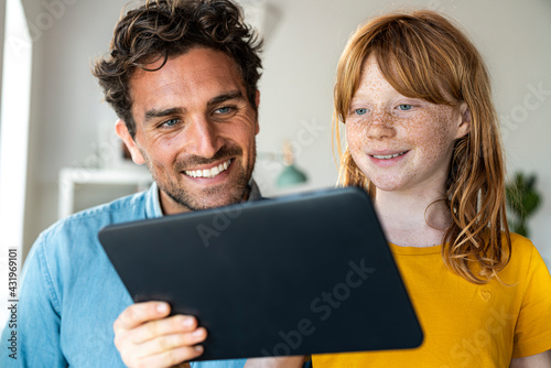 Redhead girl with father looking at laptop at home