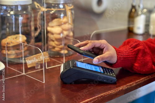 Woman paying through mobile phone at coffee shop