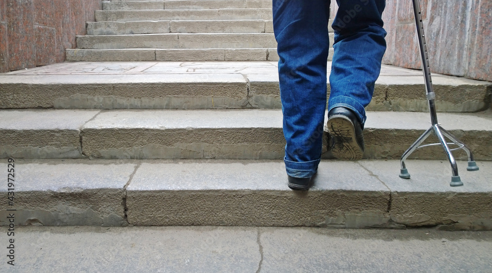 Elderly man with support cane stepping up stairs