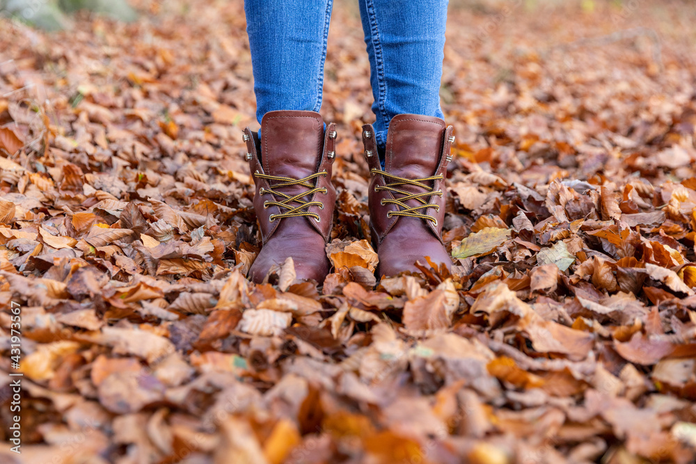 Woman in boots standing in autumn leaves while hiking in forest Woman in boots standing in autumn leaves while hiking in forest