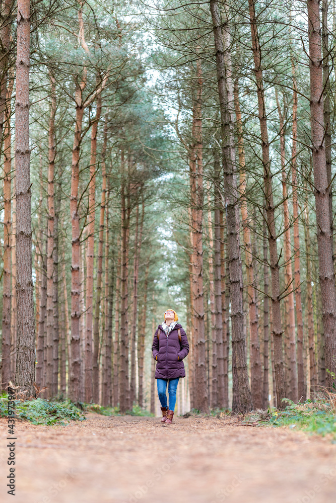 Woman with hands in pockets walking in forest Woman with hands in pockets walking in forest