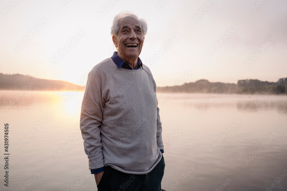 Smiling man with hands in pockets looking away while standing against sky Smiling man with hands in pockets looking away while standing against sky
