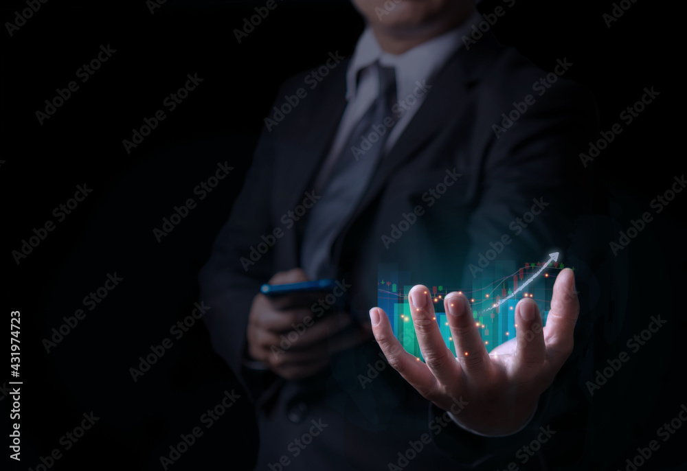 Fototapeta premium Business man holding holographic graphs and stock market statistics gain profits, Display of good economy form digital screen,Concept of growth planning and business strategy.