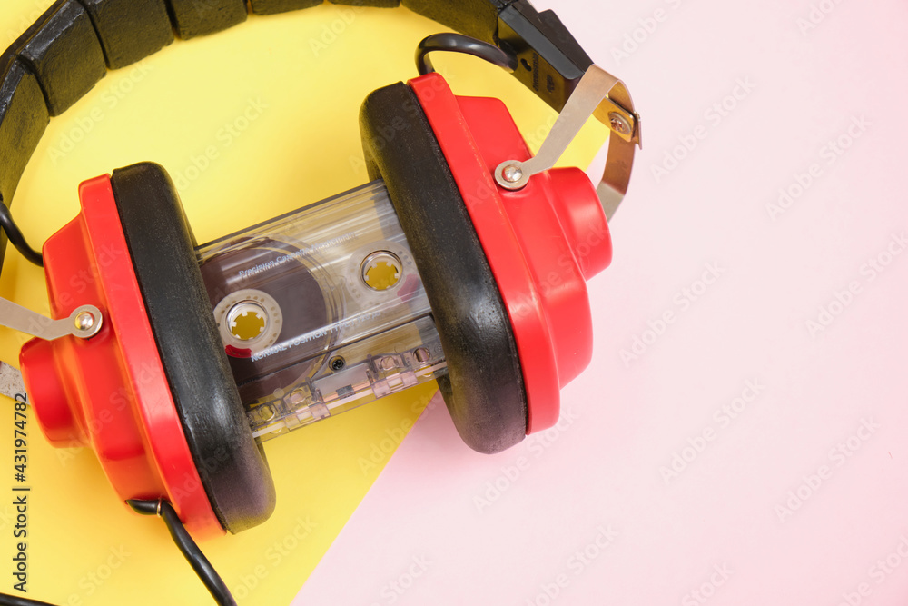 old red headphones and tape cassette on pink background