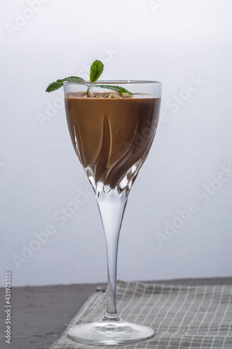 Chocolate cocktail with nuts and mint in a glass on a black background.