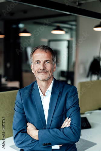 Confident male business professional with arms crossed in office