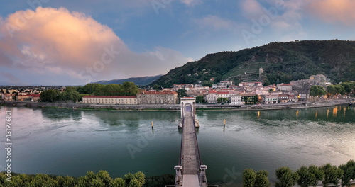 France, Ardeche, Tournon-sur-Rhone, Panorama of Passerelle Marc Seguin bridge and riverside town at dusk