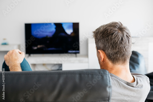 Man watching television while sitting on sofa in living room