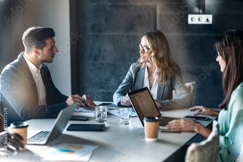Businesswoman having discussion with team while sitting in meeting at office photo