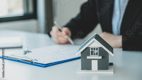 home model. Hand signing on contract after the real estate agent explains the business contract, rent, purchase, mortgage, loan, or home insurance to the buyer.