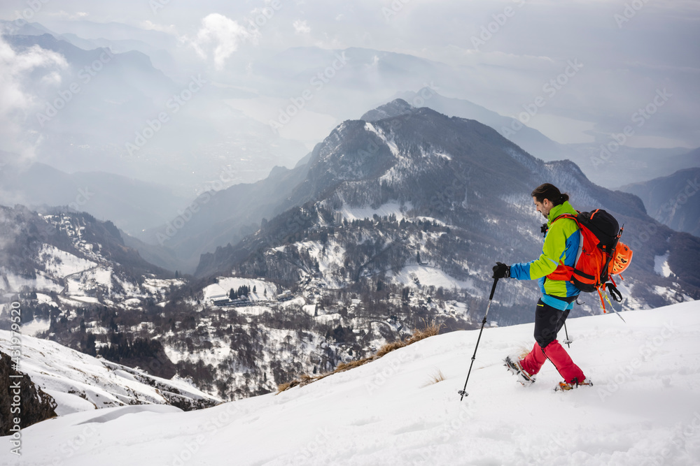 Male trekker with backpack and hiking pole walking on snowcapped mountain wearing crampon Male trekker with backpack and hiking pole walking on snowcapped mountain wearing crampon