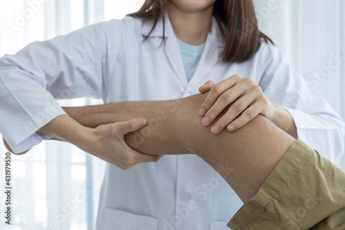 Female doctor hands doing physical therapy By extending the leg and knee of a male patient