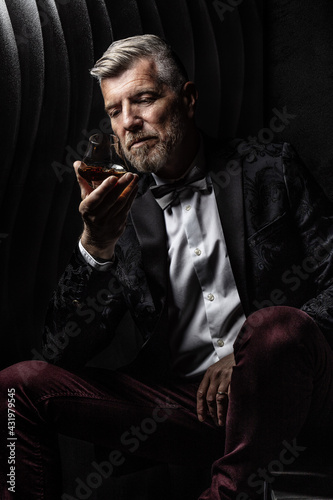 Portrait of a gentleman observing his glass of alcohol