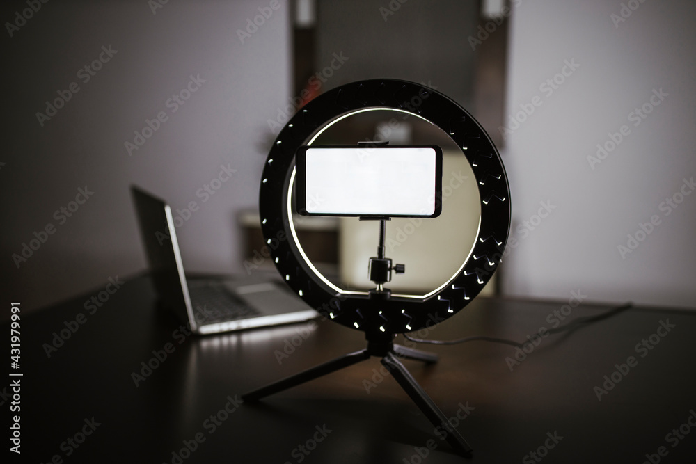 © DREAMSTOCK1982/Westend61 - Illuminated smart phone on LED ring light tripod at table