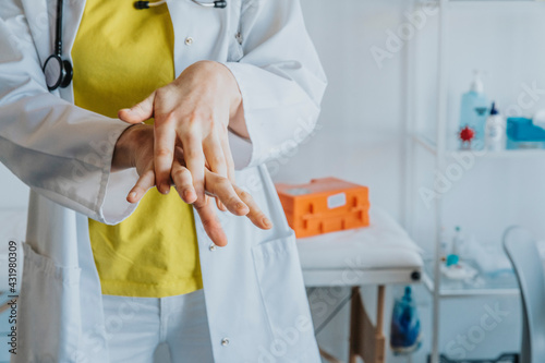 Female doctor rubbing hands with sanitizer while standing at clinic