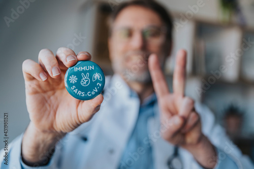 Doctor holding hand sign badge while standing at clinic photo
