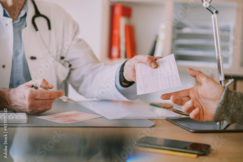 Doctor giving prescription to patient at doctor's office photo