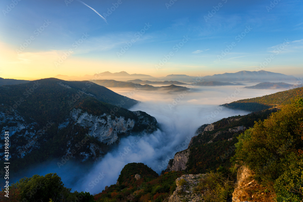 Mountains covered in fog against blue sky during sunrise at Furlo Gorge, Marche, Italy Mountains covered in fog against blue sky during sunrise at Furlo Gorge, Marche, Italy