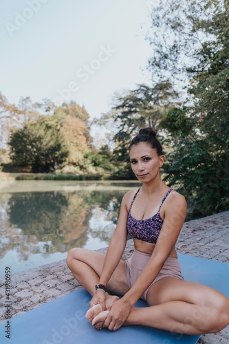 Mature athlete practicing cobbler pose while sitting on exercise mat at park photo