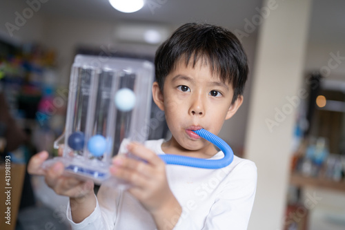 Thin boy uses a Tri-ball Incentive Spirometer for check his lung function.
