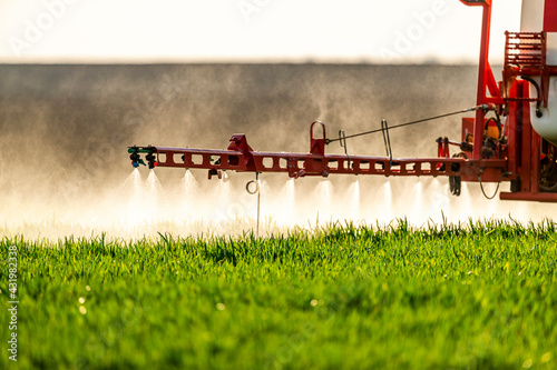 Tractor sprinkling fertilizer on crop in farm photo