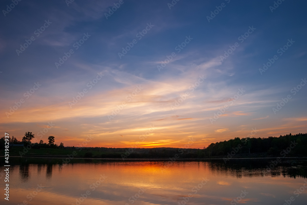 Beautiful sunset with reflection in the quiet smooth waters of the lake.