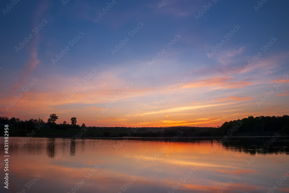 Beautiful sunset with reflection in the quiet smooth waters of the lake.