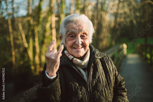 Cheerful elderly woman gesturing horn sign on sunny day