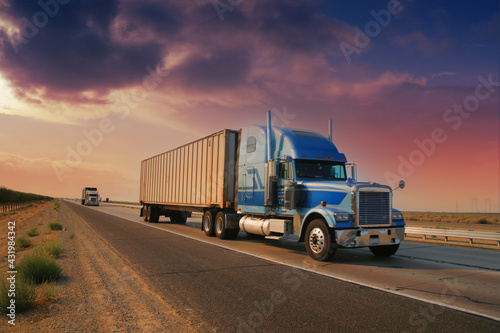Freight truck driving on highway desert road at sunset. California, USA