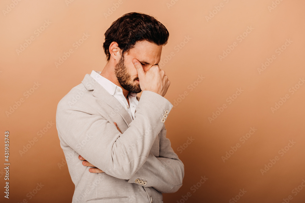 Frustrated businessman standing by brown background Frustrated businessman standing by brown background