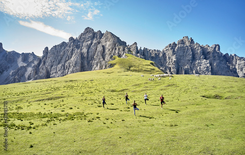 Multi-ethnic man and women practicing yoga against mountain photo