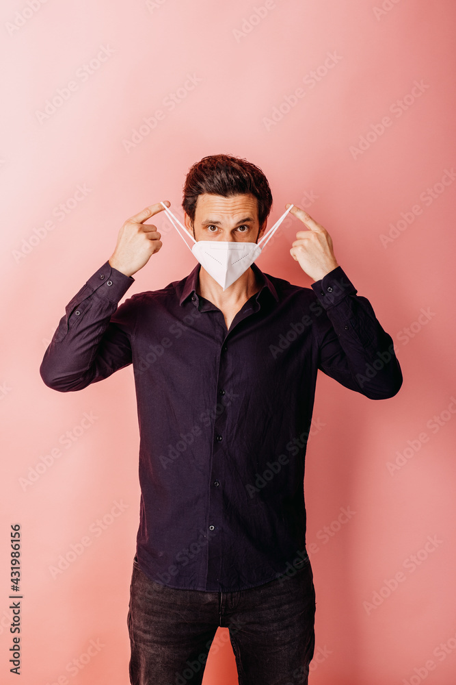 Male entrepreneur wearing protective face mask standing against colored background