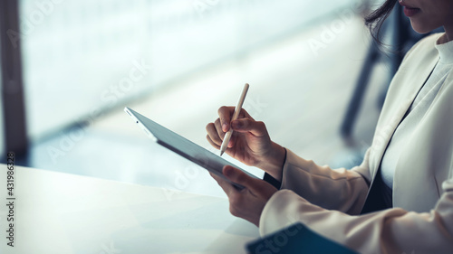 Close up of a businesswoman holding a pen working on a tablet at the office. photo