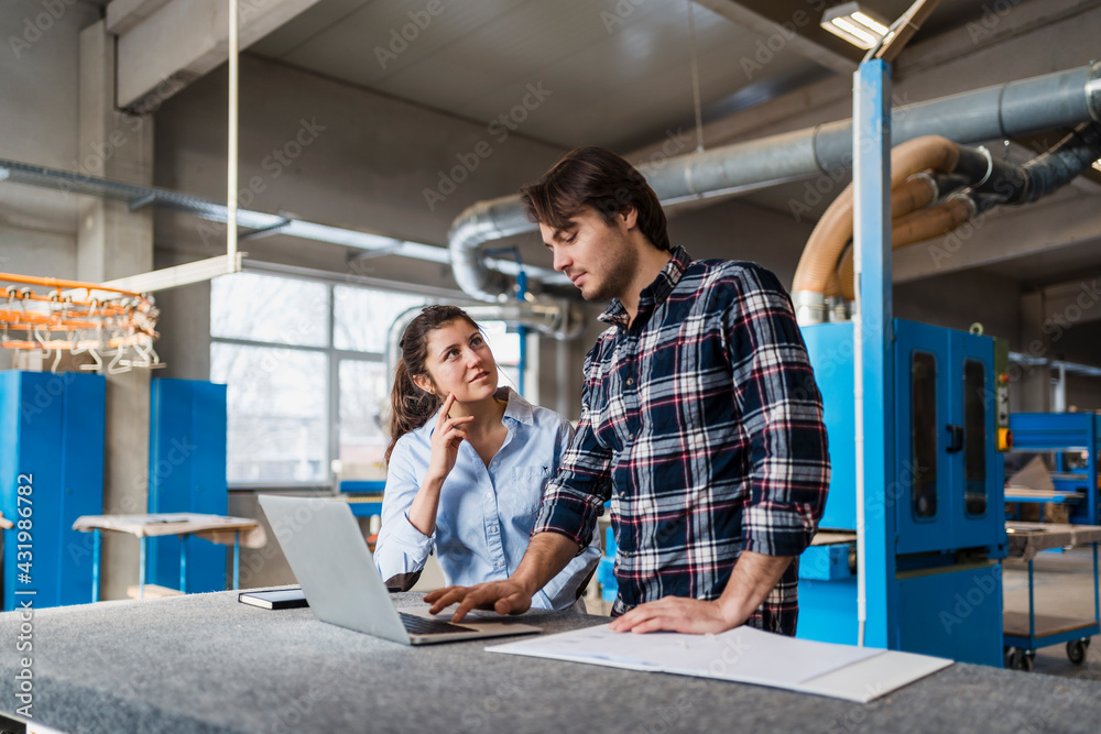 Young expertise team working over laptop while standing at industry Young expertise team working over laptop while standing at industry