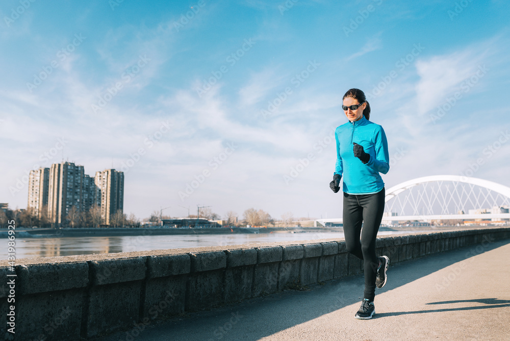 Active young woman jogging along the river in the city