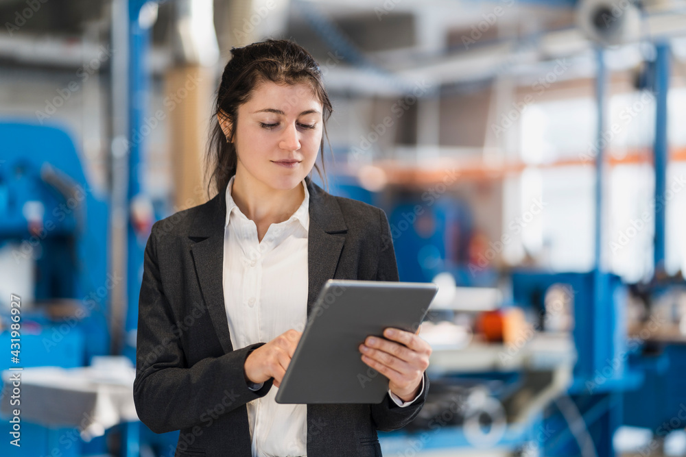 Businesswoman using digital tablet while standing at industry Businesswoman using digital tablet while standing at industry