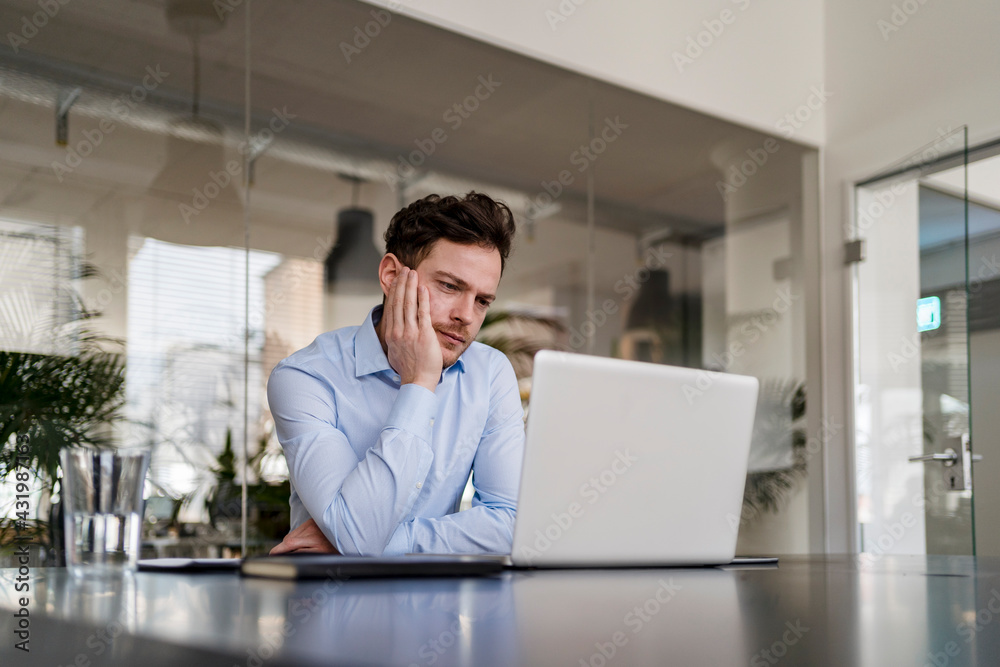 Thoughtful businessman working on laptop at office Thoughtful businessman working on laptop at office