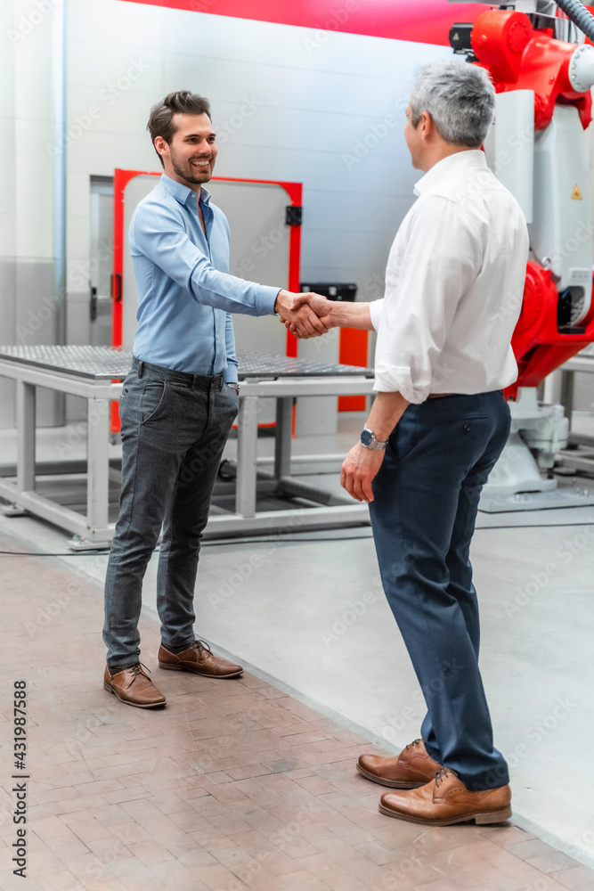 Smiling automation engineers shaking hands in industry