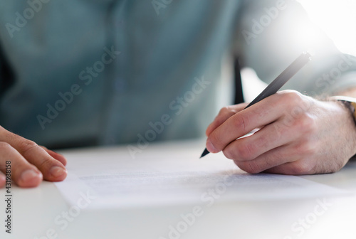 Businessman with pen filling document at office photo