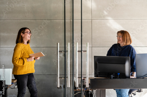 Smiling female colleagues talking in office